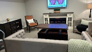 A living room with a fireplace, a television mounted above it, and a coffee table. - Cozy Apartment in Superb Fort Washington MD-Private Keyless Entry. (Fort Washington)
