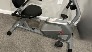 A stationary exercise bike with a black seat and grey frame, positioned against a wall with a power outlet nearby. - Cozy Apartment in Superb Fort Washington MD-Private Keyless Entry. (Fort Washington)