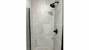 A shower area with grey tiles and a black handheld showerhead. - Cozy Apartment in Superb Fort Washington MD-Private Keyless Entry. (Fort Washington)