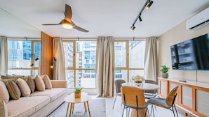 Un salon moderne comprenant un canapé, une table à manger, des chaises, un ventilateur de plafond et un téléviseur.