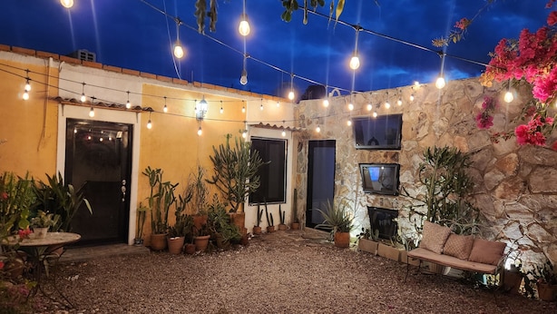 A courtyard with a stone wall, potted cacti, a sofa, and string lights. - Cozy loft # 1 just 5 minutes from the Malecon of La Paz by car. Pet Friendly! (La Paz)