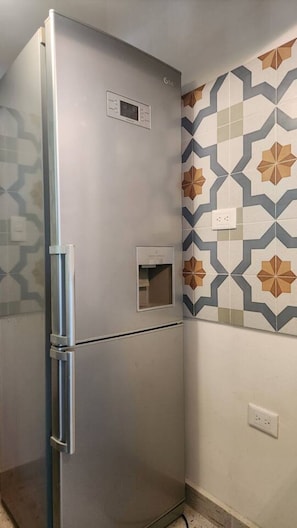 Eine Küche mit einem Edelstahl-Kühlschrank, einem Einbauofen und einer dekorativen Spritzschutzwand.