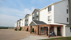 Une rangée de maisons de ville avec un espace de stationnement couvert et une moto garée à l’extérieur.