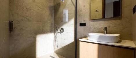A modern bathroom with a glass-enclosed shower, a sink, and a mirror.