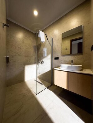 A modern bathroom with a glass-enclosed shower, a sink, and a mirror.
