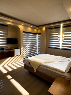 A modern bedroom with a bed, a bedside table, a TV, and a desk.
