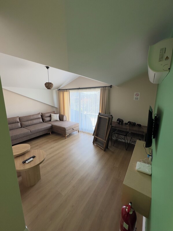 A modern living room with a sofa, a small table, a standing TV, and a fire extinguisher.