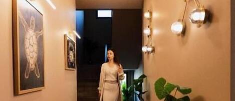 Un corridoio con una donna che cammina, illuminazione a incasso e faretti a parete.
