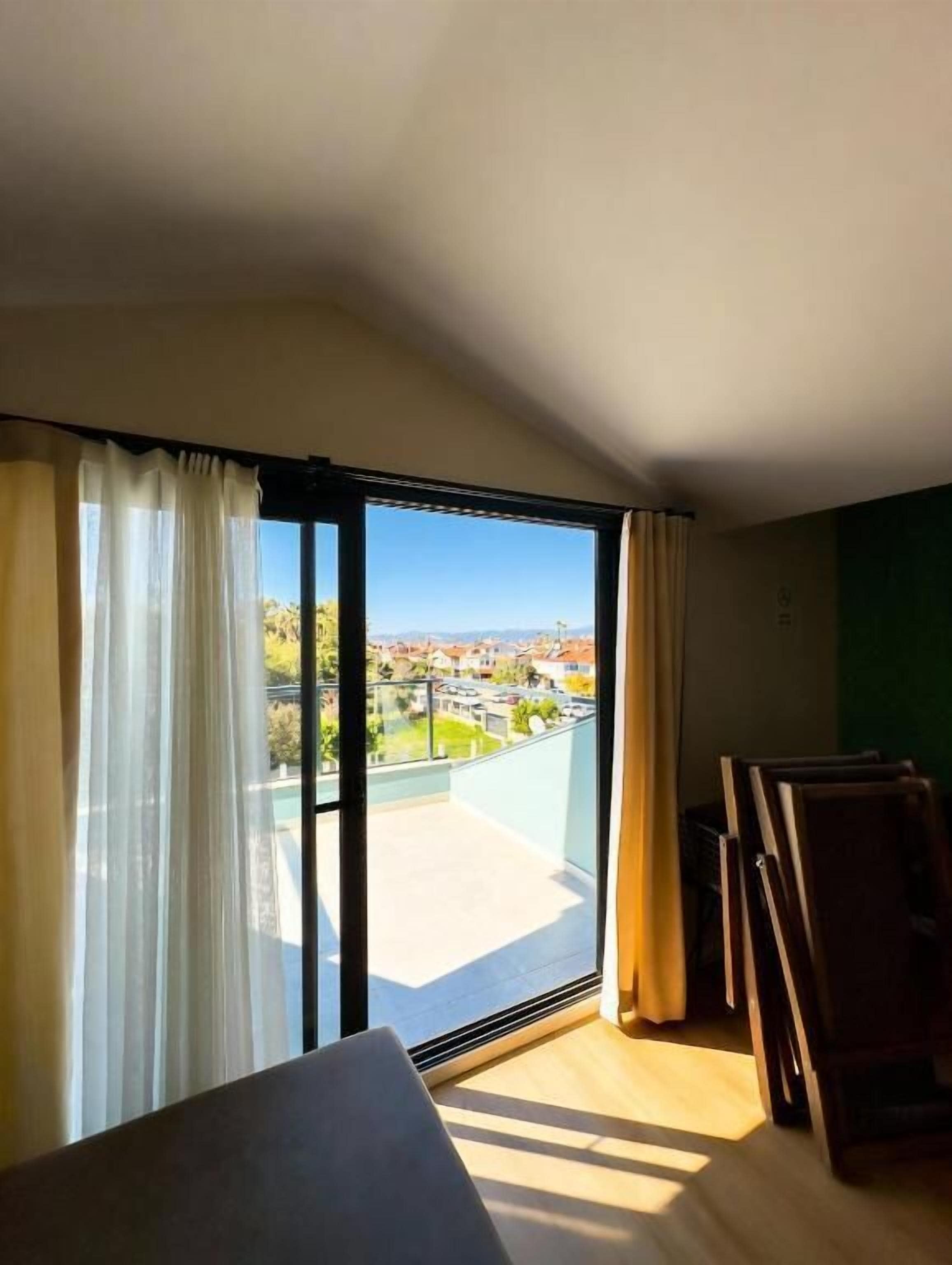 A room with a large sliding glass door leading to a balcony with a view of a residential area.