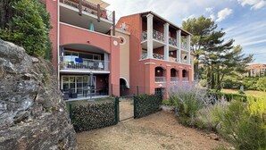 Un edificio de varios pisos con balcones, un patio y un jardín ajardinado.