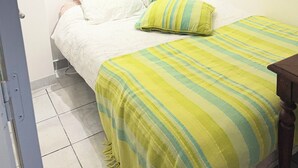 Ein Schlafzimmer mit einem Bett, Kissen, einer gestreiften Decke und einem gerahmten Bild an der Wand.