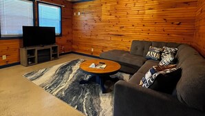A cozy room with a wooden interior, a ceiling fan, a television, a sofa, and a coffee table. - Stay in cozy cabin 5 off of Lake of the Ozarks in beautiful Sunrise Beach, MO (Sunrise Beach)