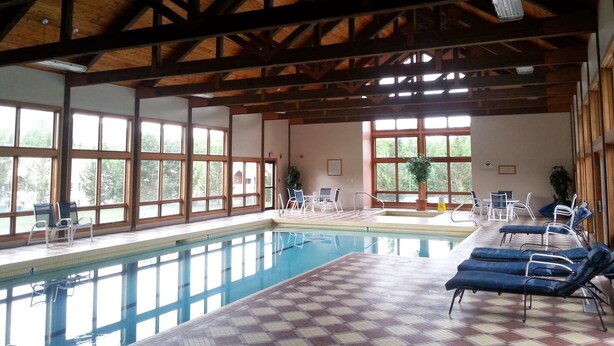 An indoor swimming pool with wooden beams, large windows, and lounge chairs. -  House in Lincoln, NH 2 Miles to Loon with Forest Ridge sports club access (Lincoln)