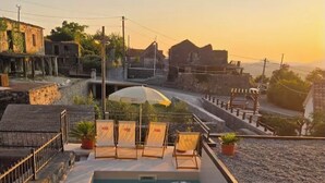 Une piscine sur le toit, agrémentée de chaises longues et de plantes en pot, offrant une vue sur une ville historique.