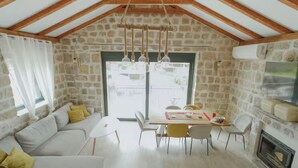 Une pièce chaleureuse avec un mur en pierre, des poutres apparentes, un canapé, une table à manger et une cheminée.