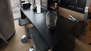 Una cucina moderna con una grande isola, sgabelli da bar neri e vista sulla città attraverso ampie finestre.