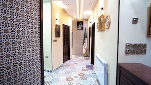 A hallway with patterned walls, a tiled floor, and a radiator on the right. - DORTOIR25CONSTANTINE (Constantine)