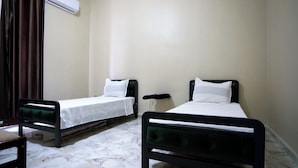 Two single beds with black frames and white bedding in a room with a marble floor. - DORTOIR25CONSTANTINE (Constantine)