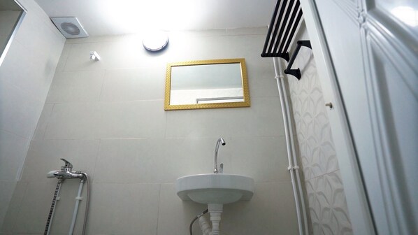 A bathroom with a white sink, a mirror with a gold frame, a shower, and a toilet. - DORTOIR25CONSTANTINE (Constantine)