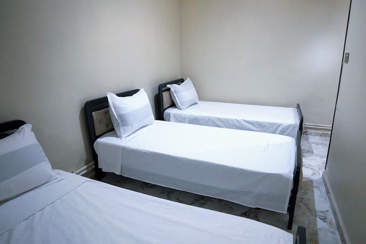 A small, clean room with two single beds and a nightstand.