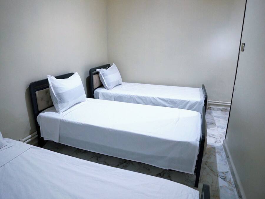 Une petite chambre propre, avec deux lits simples et une table de chevet.