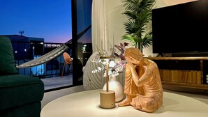 Ett rum med ett stort fönster, en staty, en tv och en växt.