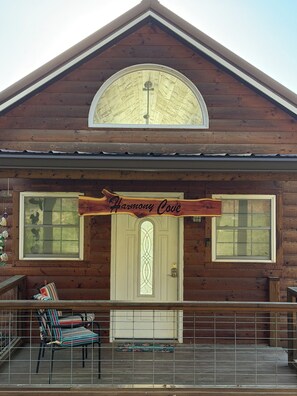 Una cabaña de madera con balcón, un amplio ventanal arqueado y un letrero que dice 'Harmony Cove'.