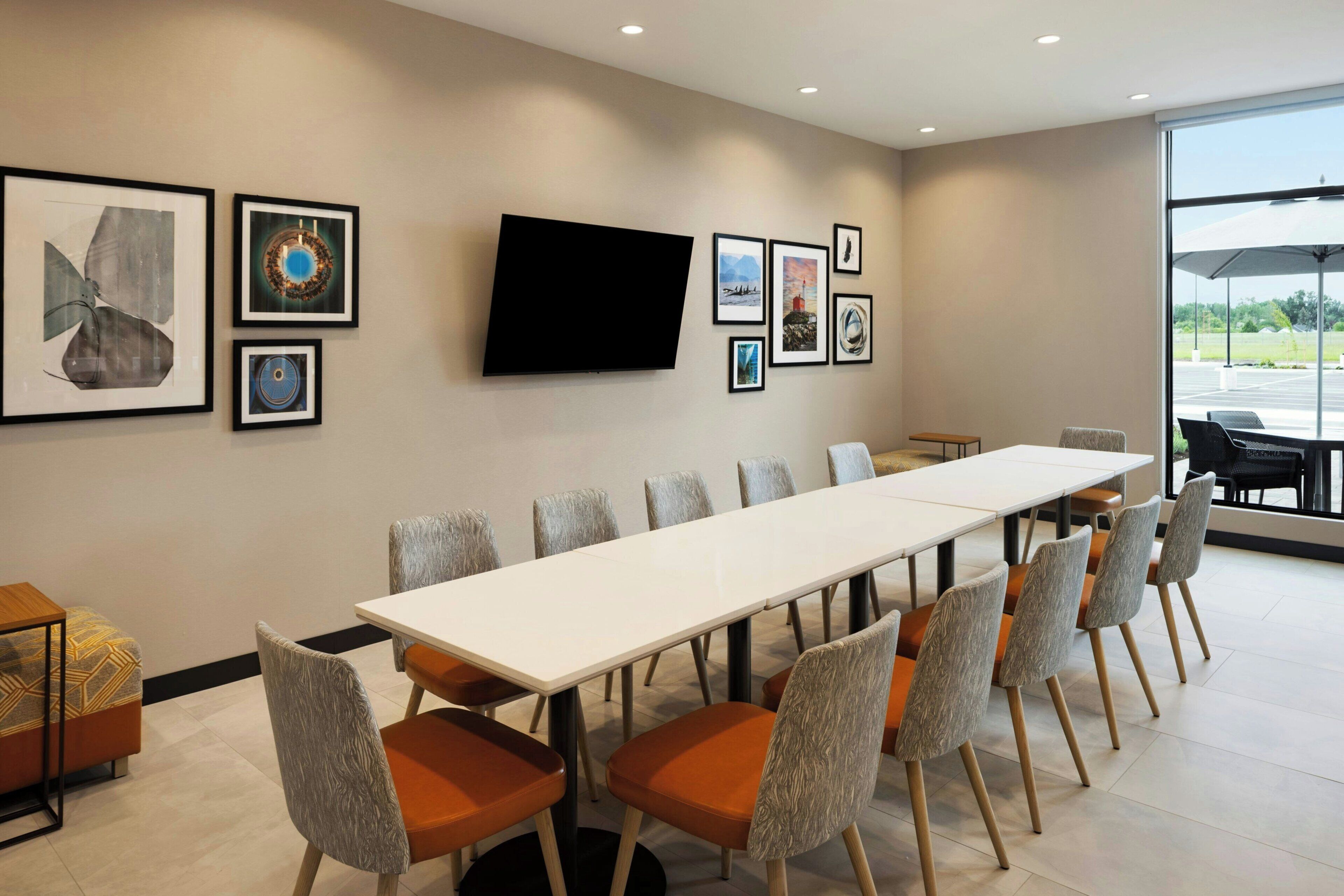 A conference room with a long table, chairs, and framed artwork on the walls.