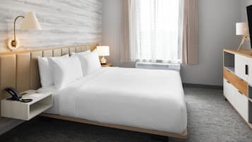 Hotelkamer met een bed, nachtkastjes, een lamp, een telefoon, een raam met gordijnen en een muur met een structuur.