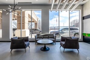 A modern interior with large windows, a round table, and three sofas. - Landing | Amazing 1BD, Game Room, Yoga Studio (Hartford)