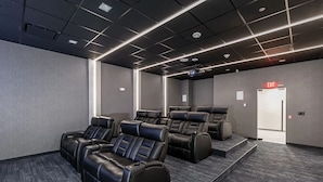 Un'elegante sala home theater con poltrone reclinabili, un proiettore e un pavimento rivestito di moquette.