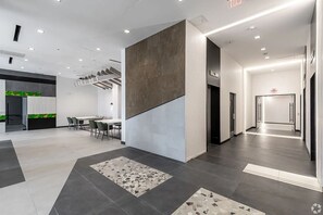 A modern office space with a meeting area, a staircase, and a hallway leading to an exit. - Landing | Beautiful 1BD, Game Room, Pool (Hartford)