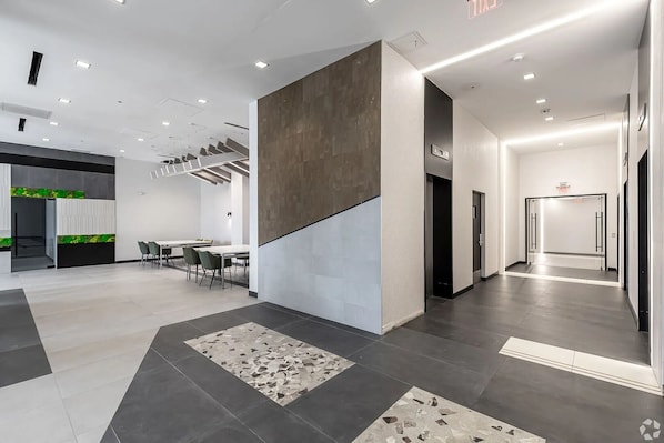 A modern interior with a conference room, a staircase, and a hallway leading to an exit. - Landing | Beautiful 1BD, Game Room, Gym (Hartford)