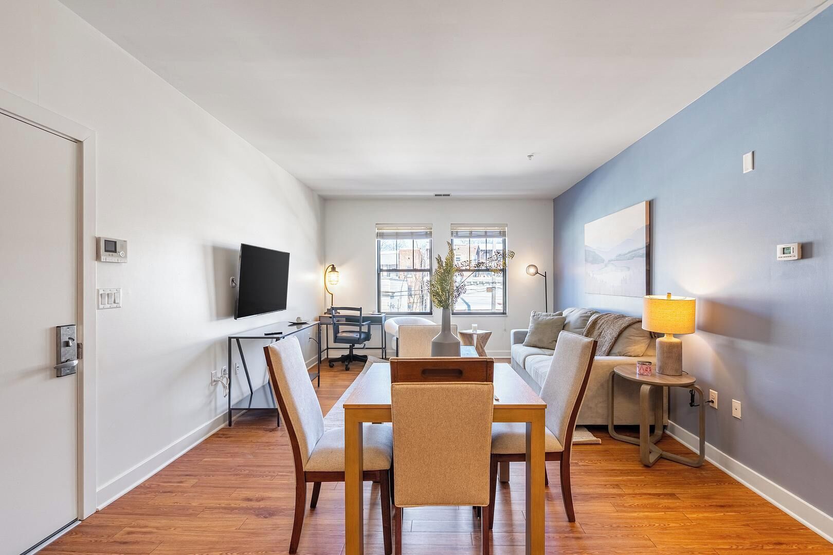Un appartement moderne comprenant un coin repas, un téléviseur, un canapé et une lampe.