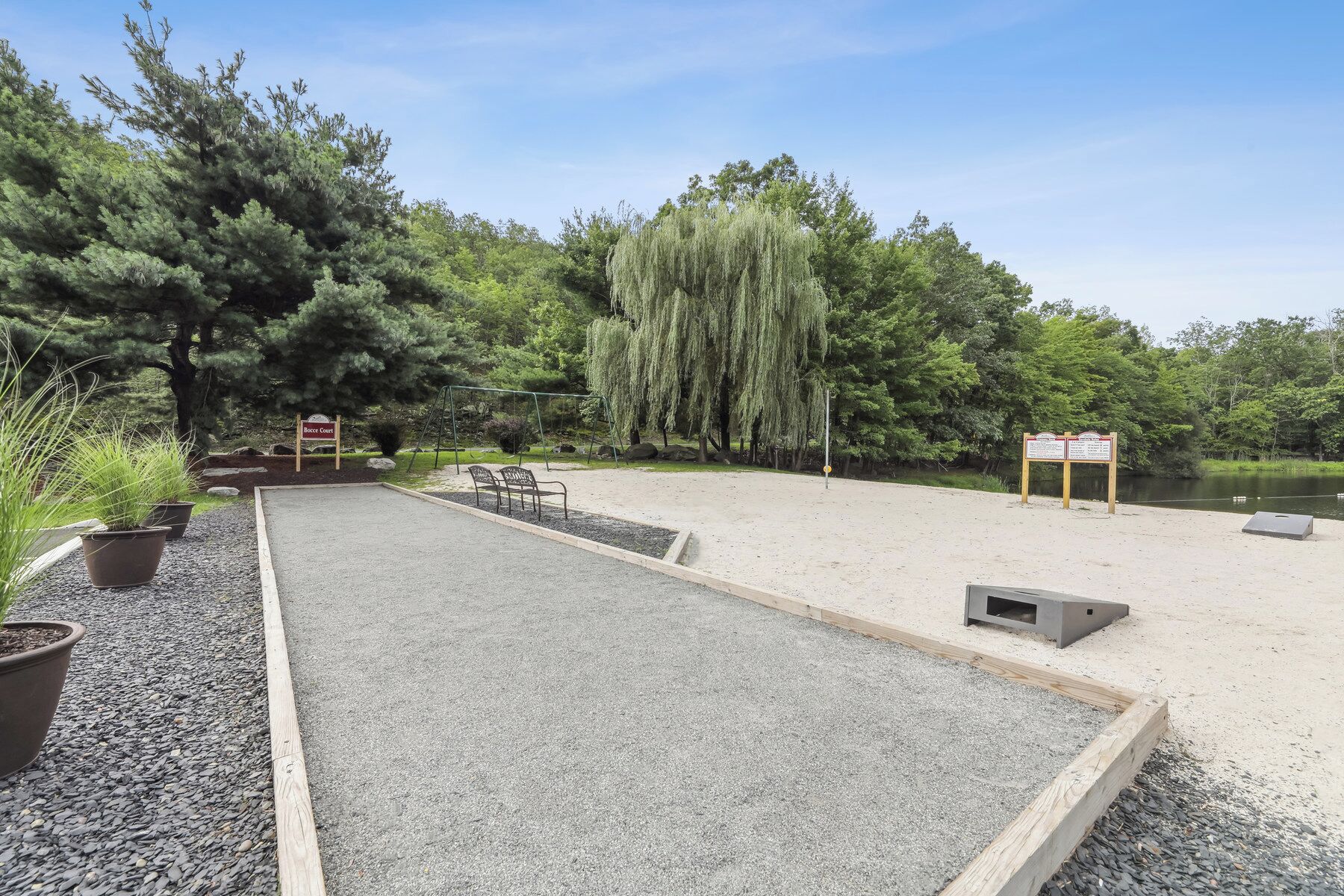 Ein Kiesparkplatz mit Schaukel, Picknicktischen und einem Schild mit der Aufschrift 'Boscocourt'.