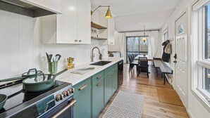 Una cocina moderna con armarios blancos, una isla central y una zona de comedor con banco y mesa.