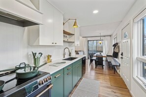 A modern kitchen with white cabinets, a central island, and a dining area with a bench and table.