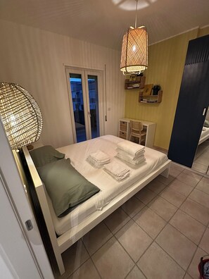 Un dormitorio moderno con cama, lámparas de noche, escritorio y armario.