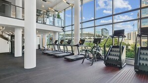 Een moderne sportschool met loopbanden en elliptische machines, grote ramen en uitzicht op de stad.