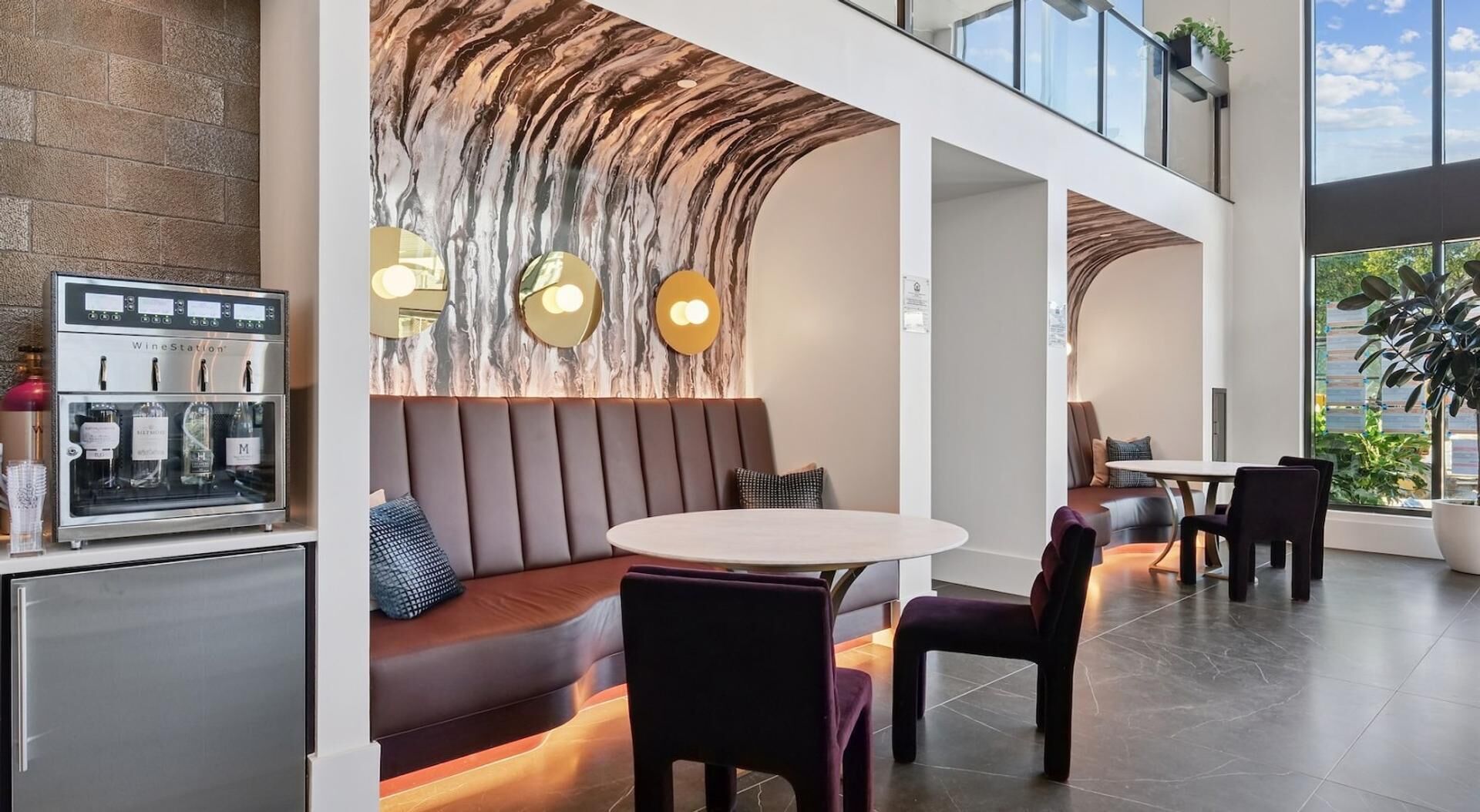 A modern interior with a marble wall, a wine station, and seating areas.