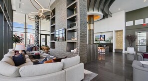 Eine großzügige Lobby mit modernem Design, ausgestattet mit einer gemütlichen Sitzecke, einer Bar und einem Fernseher.