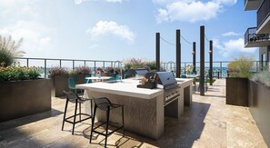 Una terraza en la azotea con zona de bar, asientos al aire libre y vistas de la ciudad.
