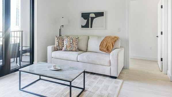 Una sala moderna con un sofá, una mesa de centro y un cuadro en la pared.
