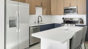A modern kitchen with stainless steel appliances, wooden cabinets, and a central island. - Landing | Chic 1BD in Uptown Charlotte (Charlotte)