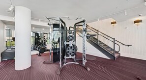A gym with weightlifting equipment, a treadmill, and a staircase. - Landing | Chic 1BD in Uptown Charlotte (Charlotte)