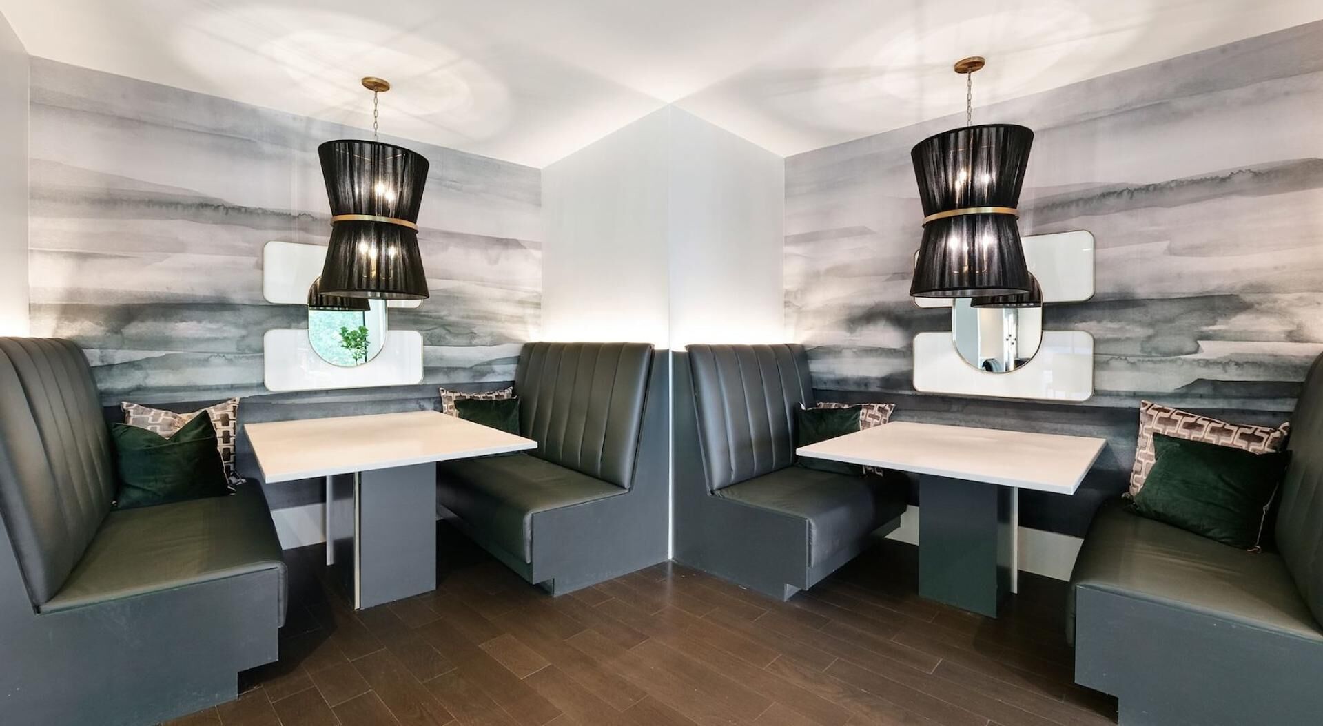 A restaurant with booth seating, pendant lighting, and a marble wall backsplash.