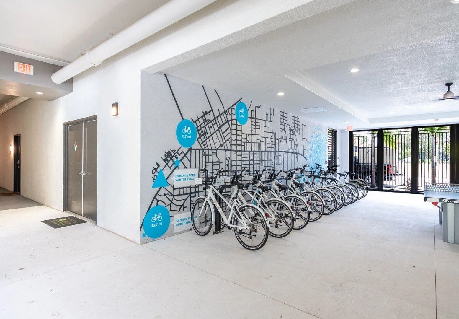 Una stazione di noleggio biciclette con biciclette disposte lungo un muro, una mappa e indicatori di distanza.