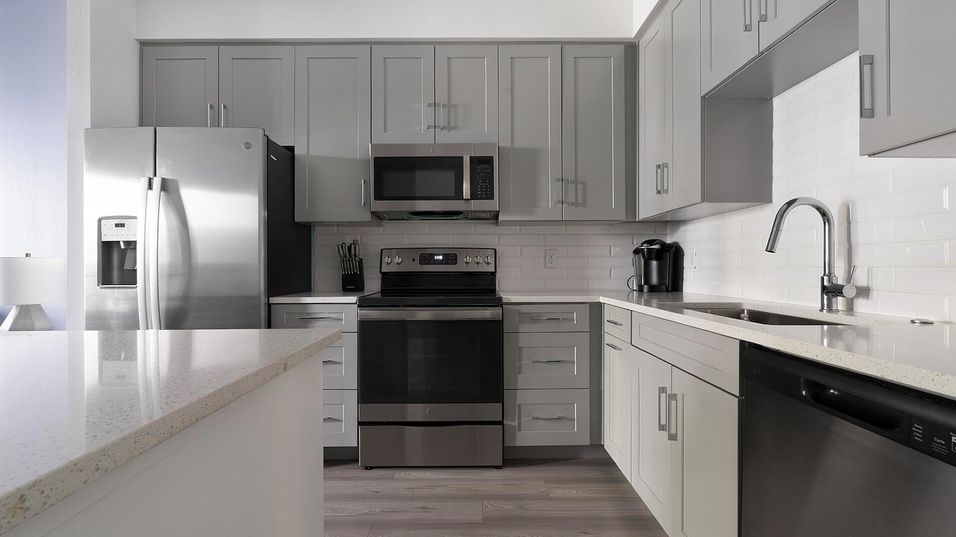 A modern kitchen with stainless steel appliances, white cabinetry, and a granite countertop.