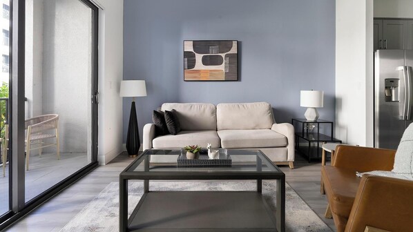 A modern living room with a sofa, coffee table, and two lamps. - Landing | Stunning 1BD, Gym, Game Room (Fort Myers)