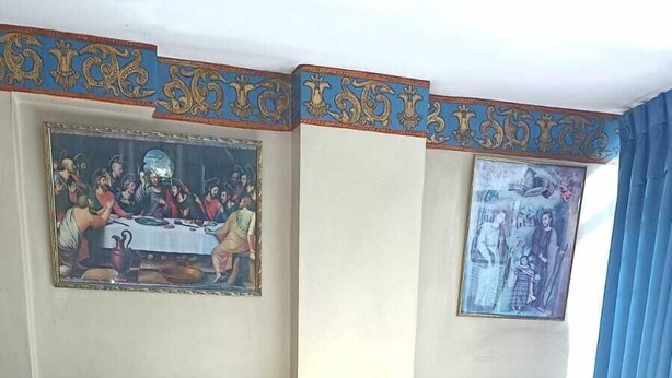 A hotel room with a large bed, floral bedspread, two towels, a wooden headboard, and two framed artworks on the walls. - Samana Wasi Urpicha (Cusco)